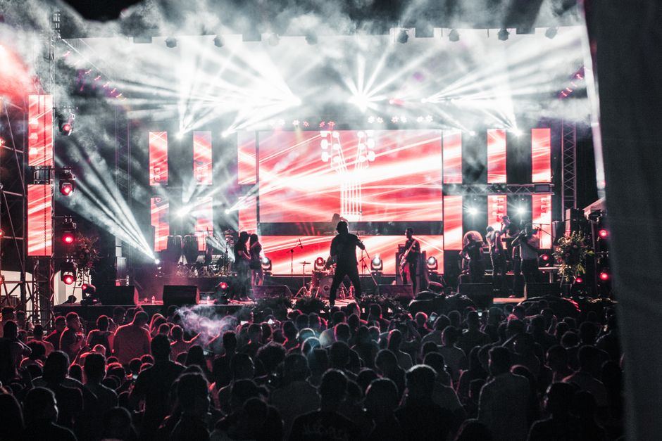 Concert live cu scenă iluminată și public numeros