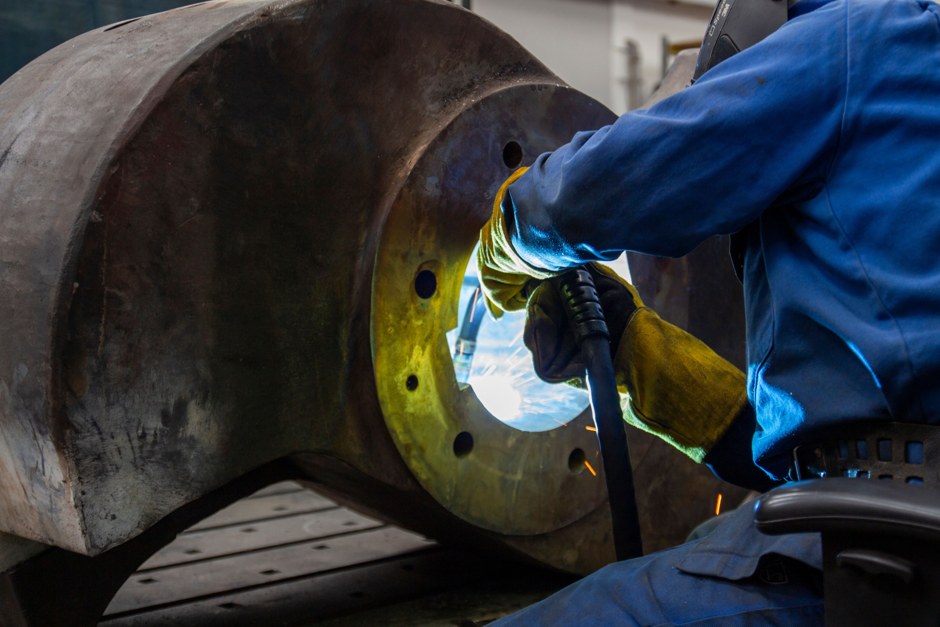 Sudor lucrând la un utilaj industrial de mari dimensiuni